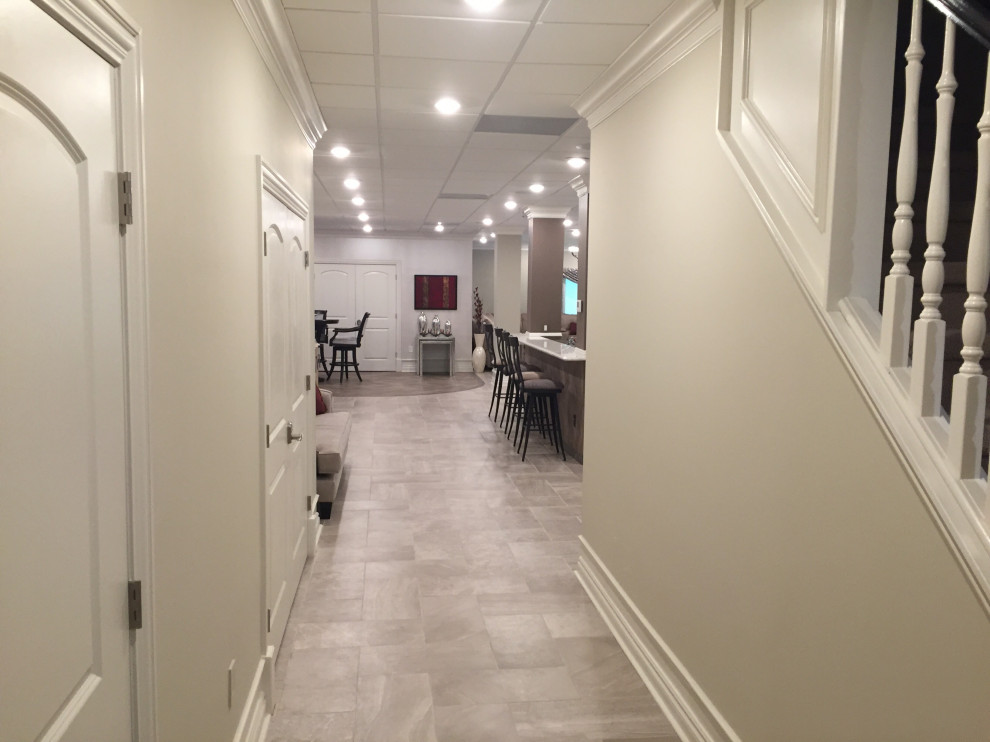 Expansive transitional walk-out basement in Chicago with beige walls, porcelain floors, no fireplace and grey floor.