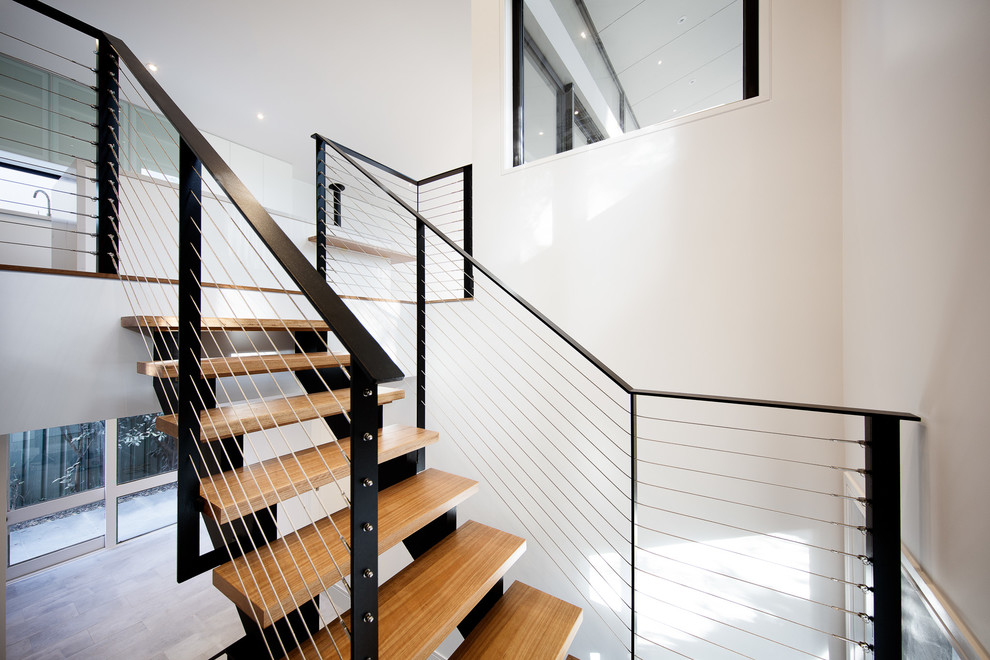 Inspiration for a mid-sized contemporary wood u-shaped staircase in Melbourne with open risers and cable railing.