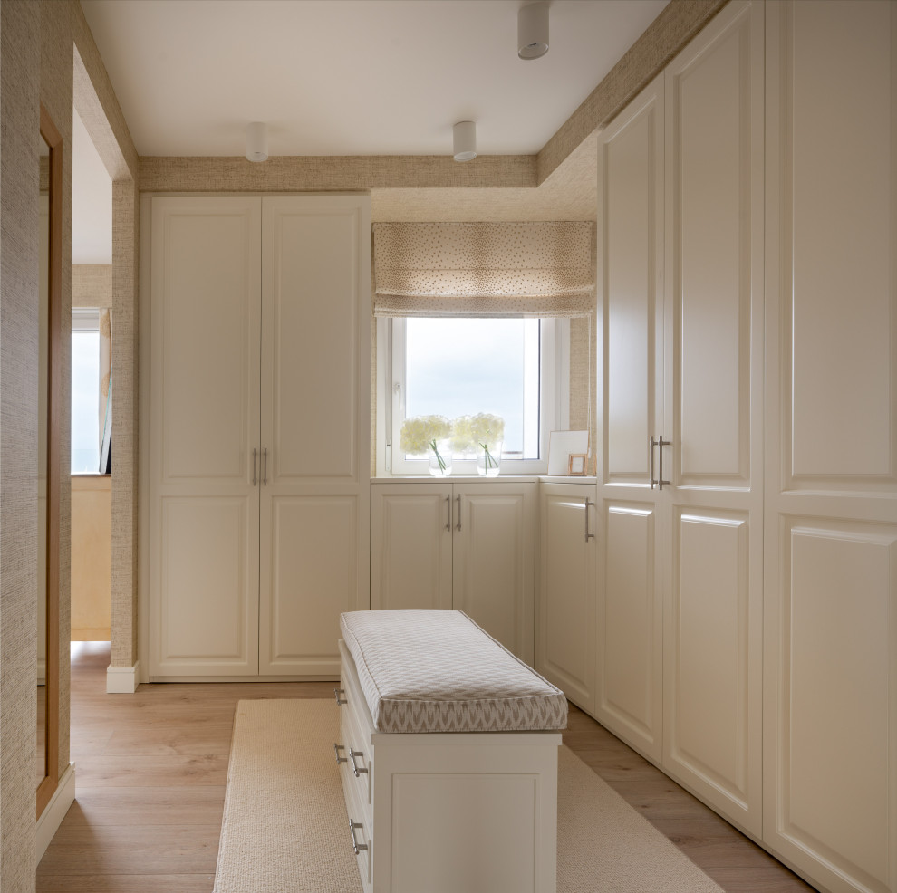 Large transitional gender-neutral walk-in wardrobe in Bilbao with raised-panel cabinets, white cabinets, laminate floors and brown floor.