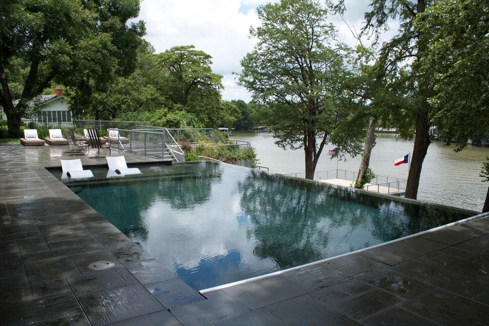This is an example of a mid-sized modern backyard rectangular infinity pool in Austin with a hot tub and tile.
