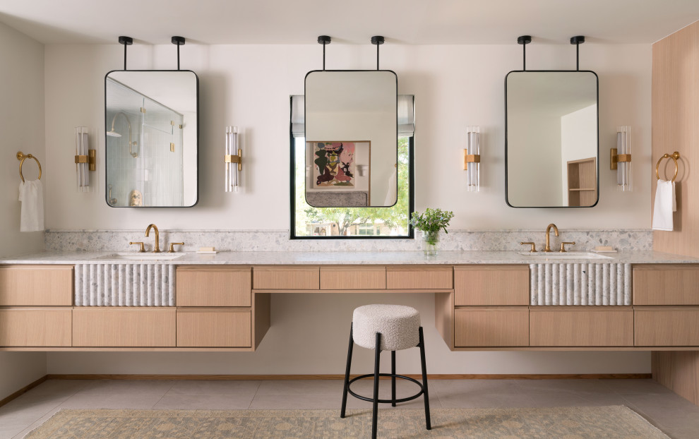 オースティンにあるトランジショナルスタイルのおしゃれなマスターバスルーム (淡色木目調キャビネット、置き型浴槽、白い壁、アンダーカウンター洗面器、ニッチ、洗面台2つ、フローティング洗面台) の写真