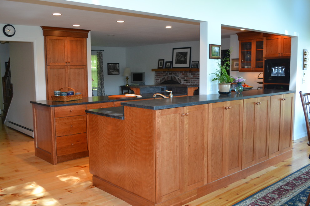 Large traditional eat-in kitchen in Boston with an undermount sink, shaker cabinets, medium wood cabinets, granite benchtops, black appliances and light hardwood floors.
