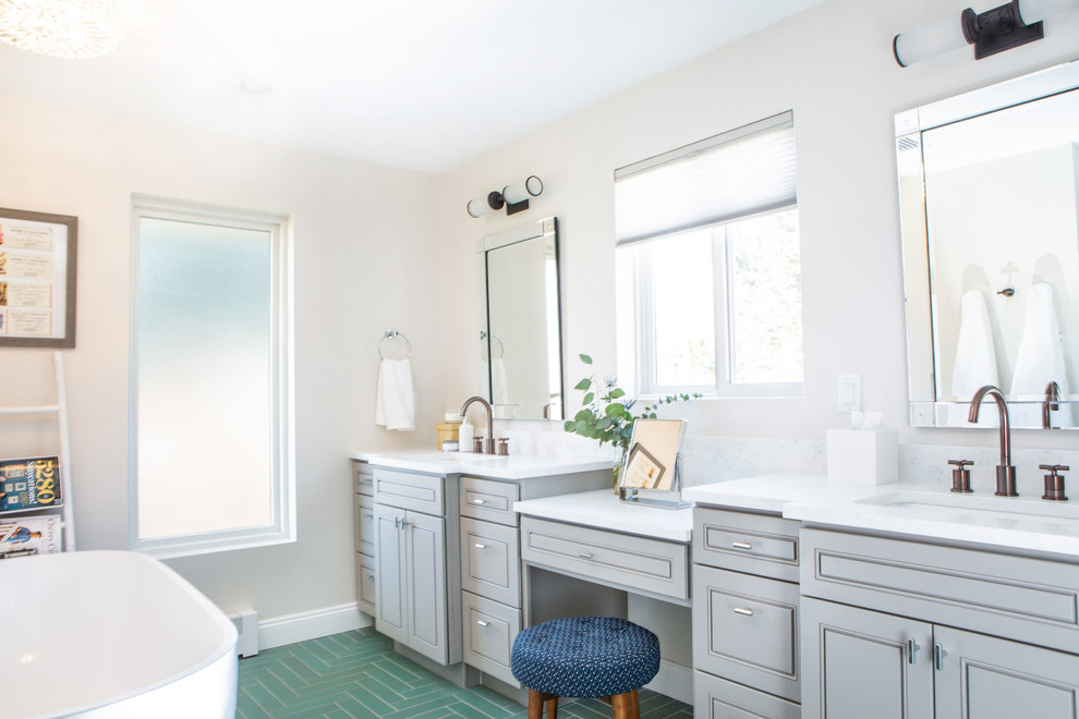 Photo of a large transitional master bathroom in Denver with raised-panel cabinets, grey cabinets, a freestanding tub, an alcove shower, a one-piece toilet, green tile, ceramic tile, white walls, ceramic floors, an undermount sink, engineered quartz benchtops, green floor, a hinged shower door and white benchtops.