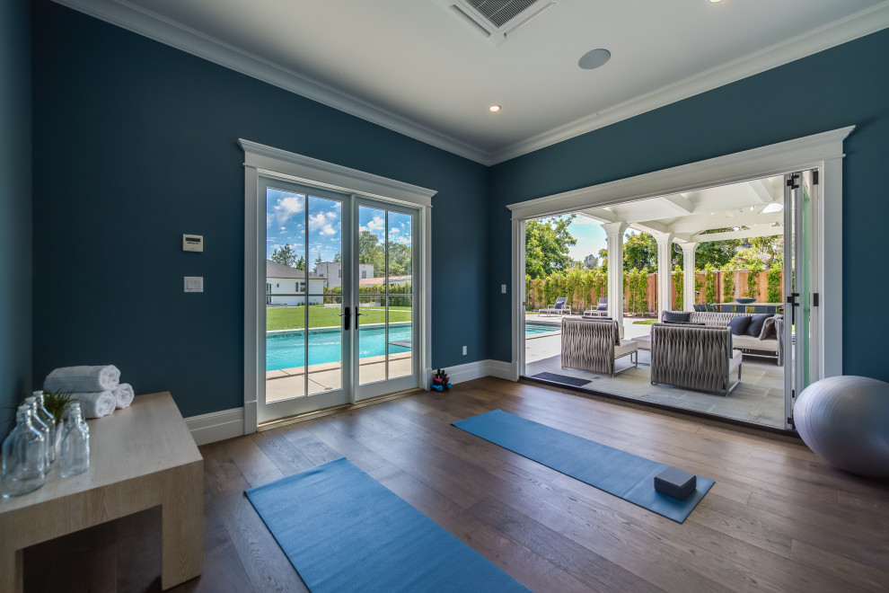 Immagine di uno studio yoga chic di medie dimensioni con pareti blu, pavimento in legno massello medio e pavimento marrone