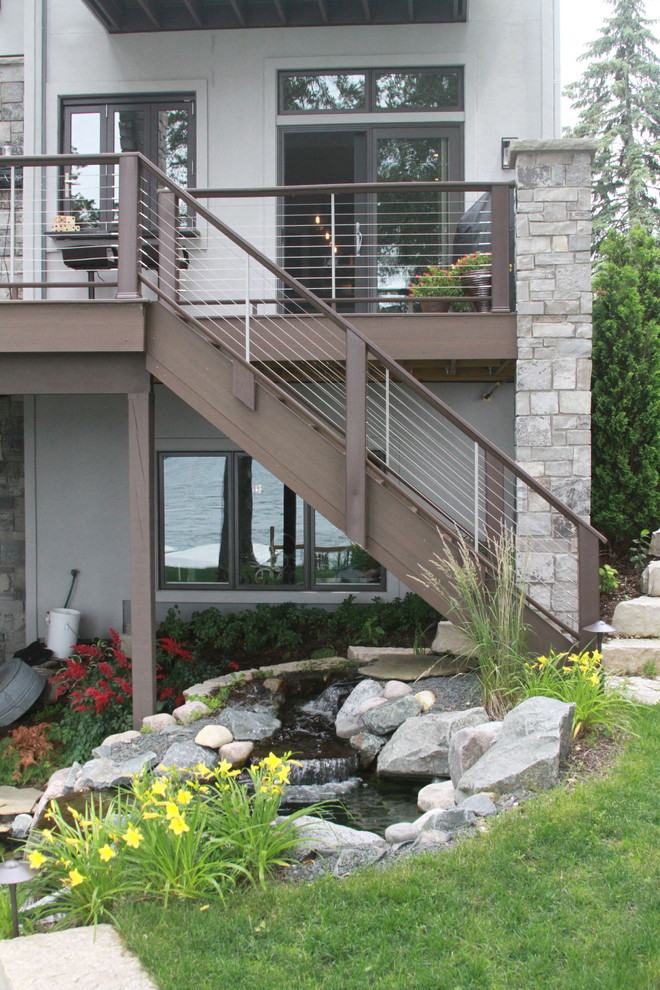 Photo of a large transitional backyard deck in Milwaukee with a pergola.