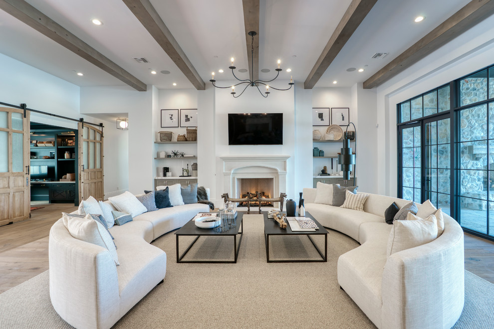 This is an example of a large transitional enclosed family room in Phoenix with white walls, light hardwood floors, a standard fireplace, a wall-mounted tv and beige floor.