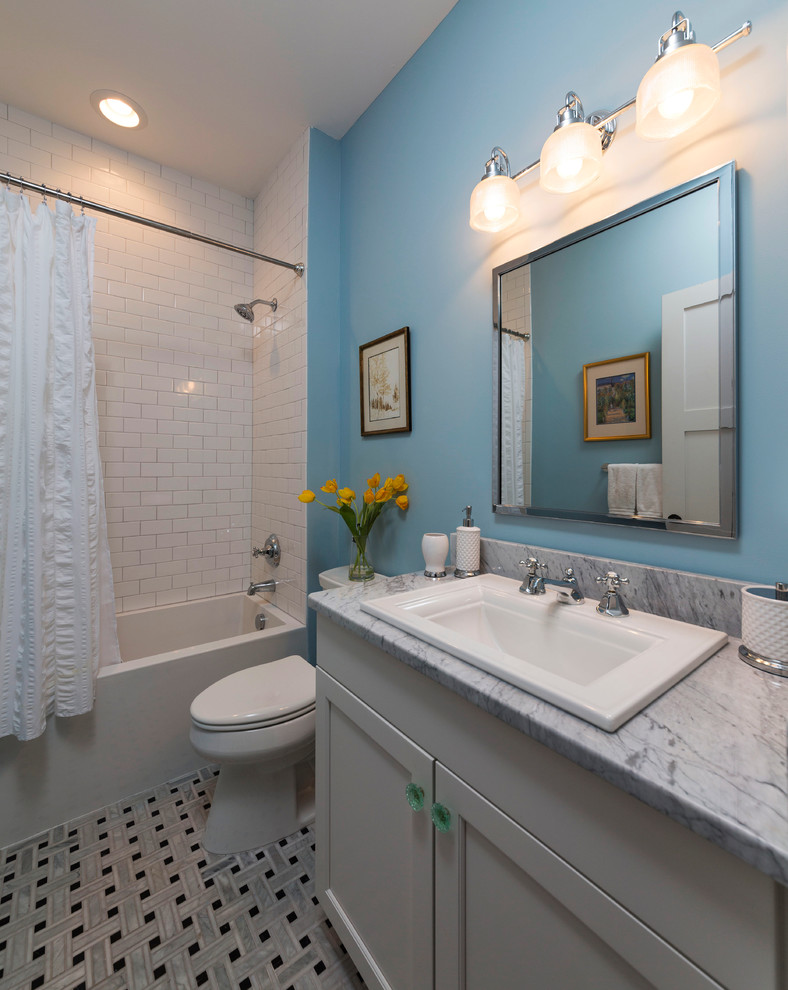 Photo of a small transitional bathroom in Richmond with a drop-in sink, shaker cabinets, white cabinets, marble benchtops, an alcove tub, a shower/bathtub combo, a two-piece toilet, white tile, mosaic tile, blue walls and marble floors.