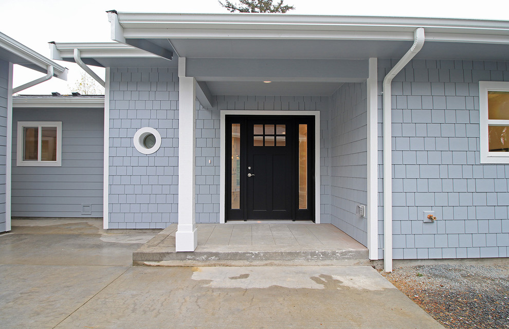 Inspiration for a mid-sized beach style front door in Seattle with a single front door, blue walls, concrete floors and a black front door.