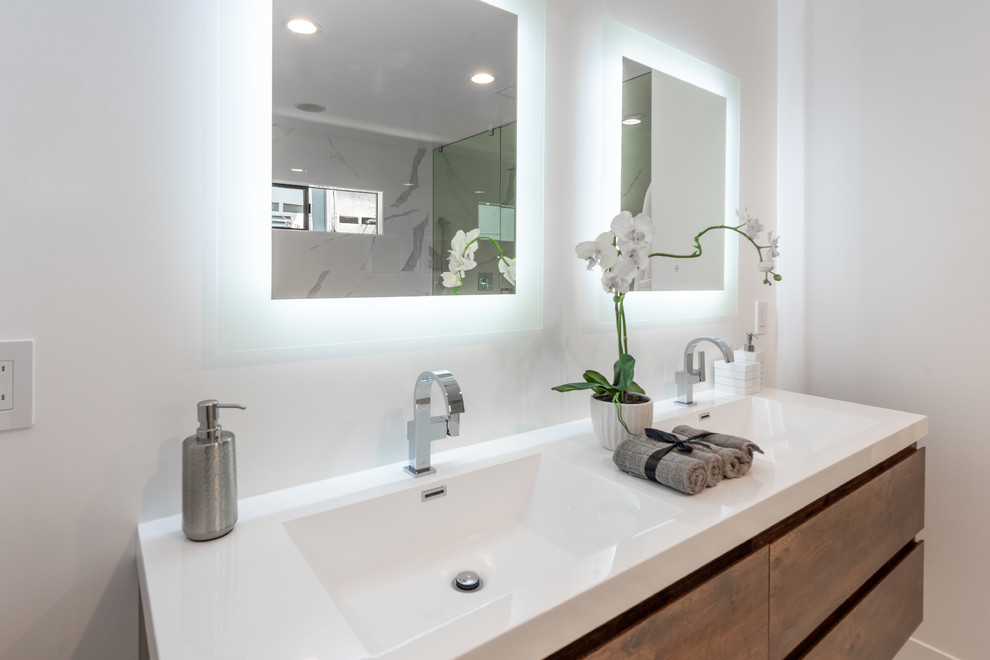 Design ideas for a large contemporary master bathroom in Los Angeles with flat-panel cabinets, brown cabinets, a freestanding tub, a double shower, a two-piece toilet, white tile, porcelain tile, white walls, porcelain floors, an integrated sink, engineered quartz benchtops, white floor, a hinged shower door and white benchtops.