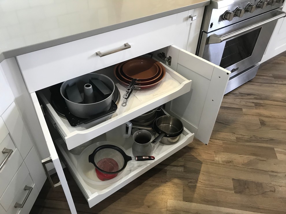 Inspiration for a large transitional single-wall light wood floor and gray floor eat-in kitchen remodel in Atlanta with a farmhouse sink, shaker cabinets, white cabinets, quartzite countertops, white backsplash, marble backsplash, stainless steel appliances, an island and white countertops
