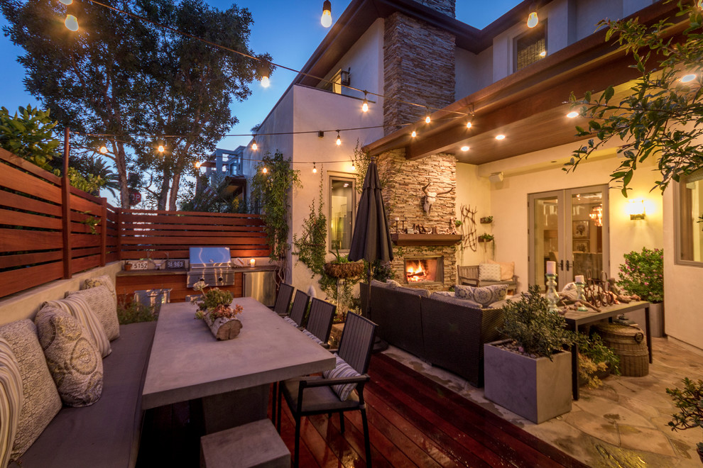 Photo of a large transitional backyard patio in Los Angeles with an outdoor kitchen, natural stone pavers and a roof extension.