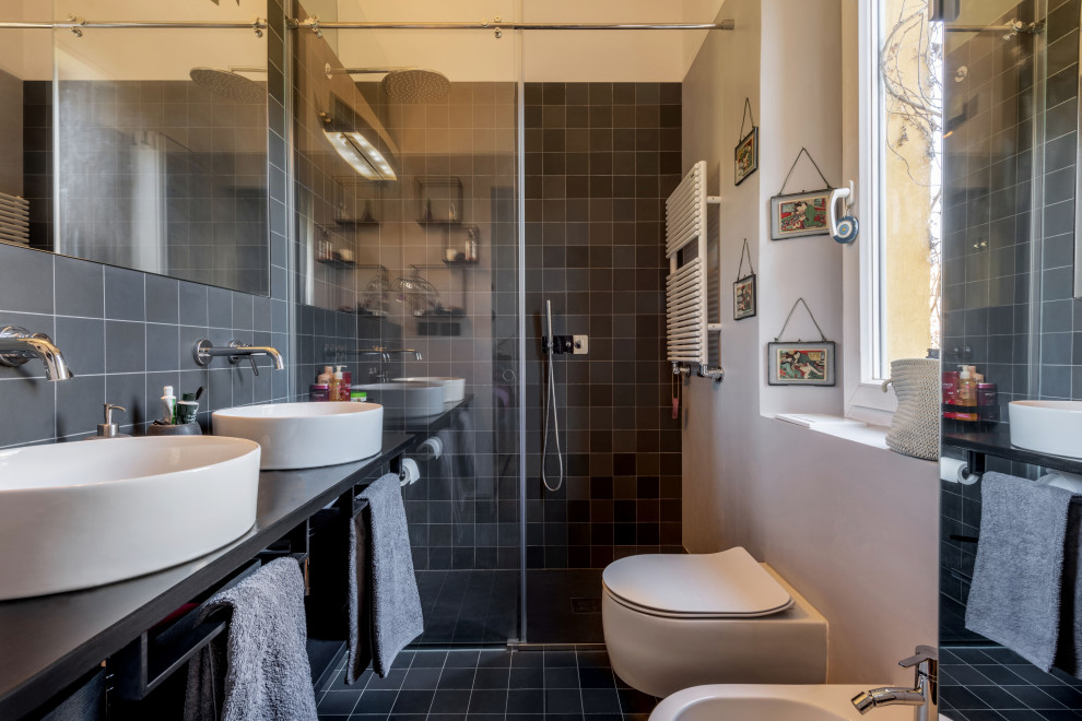 Idées déco pour une petite salle d'eau contemporaine avec des portes de placard noires, une douche à l'italienne, WC suspendus, un carrelage noir, des carreaux de porcelaine, un mur gris, un sol en carrelage de porcelaine, une vasque, un plan de toilette en calcaire, un sol noir, une cabine de douche à porte coulissante, un plan de toilette noir, meuble double vasque et meuble-lavabo suspendu.