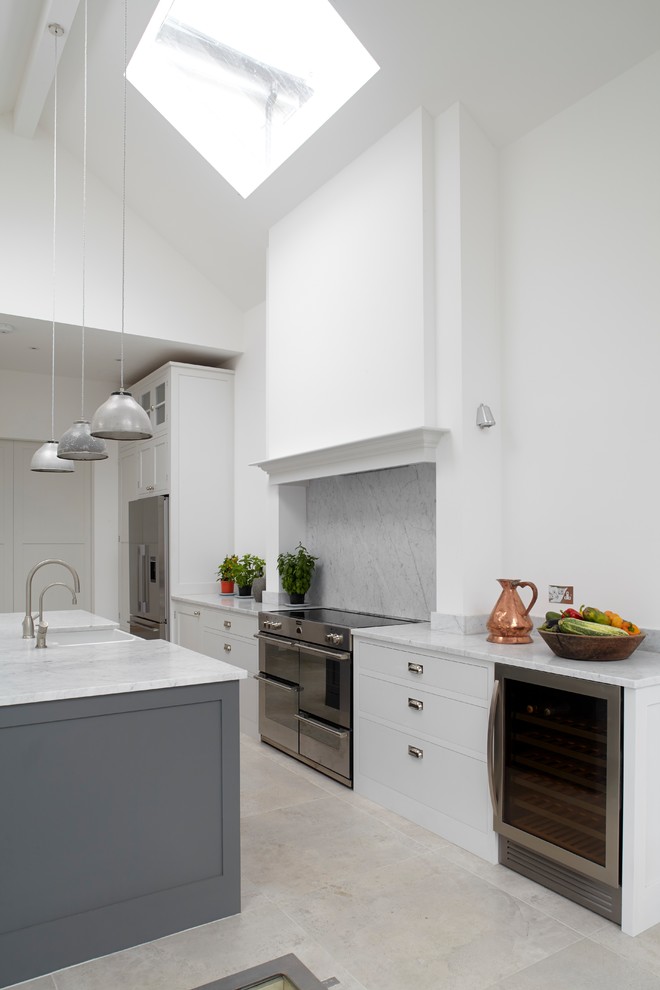 Photo of a mid-sized traditional open plan kitchen in London with a farmhouse sink, shaker cabinets, grey cabinets, marble benchtops, marble splashback, stainless steel appliances, porcelain floors and with island.