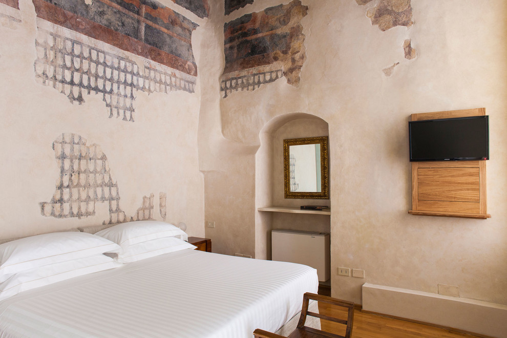 Photo of a mediterranean bedroom in Florence with beige walls, medium hardwood floors and brown floor.