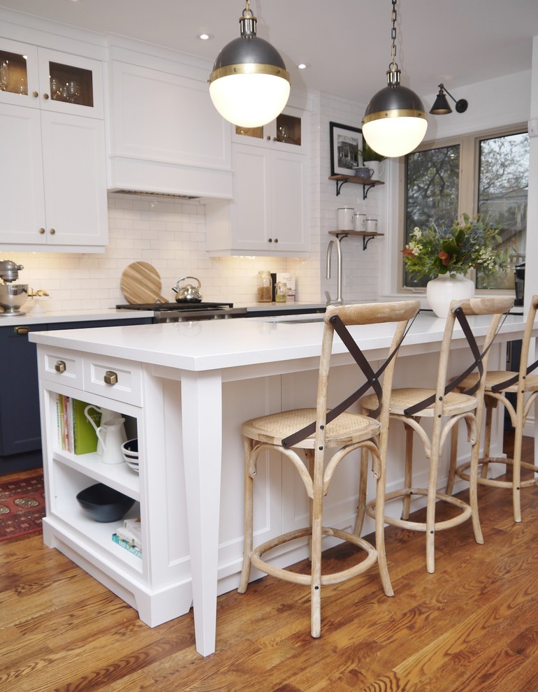 Example of a mid-sized transitional l-shaped medium tone wood floor and brown floor eat-in kitchen design in Toronto with an undermount sink, shaker cabinets, blue cabinets, quartz countertops, white backsplash, subway tile backsplash, stainless steel appliances, an island and white countertops