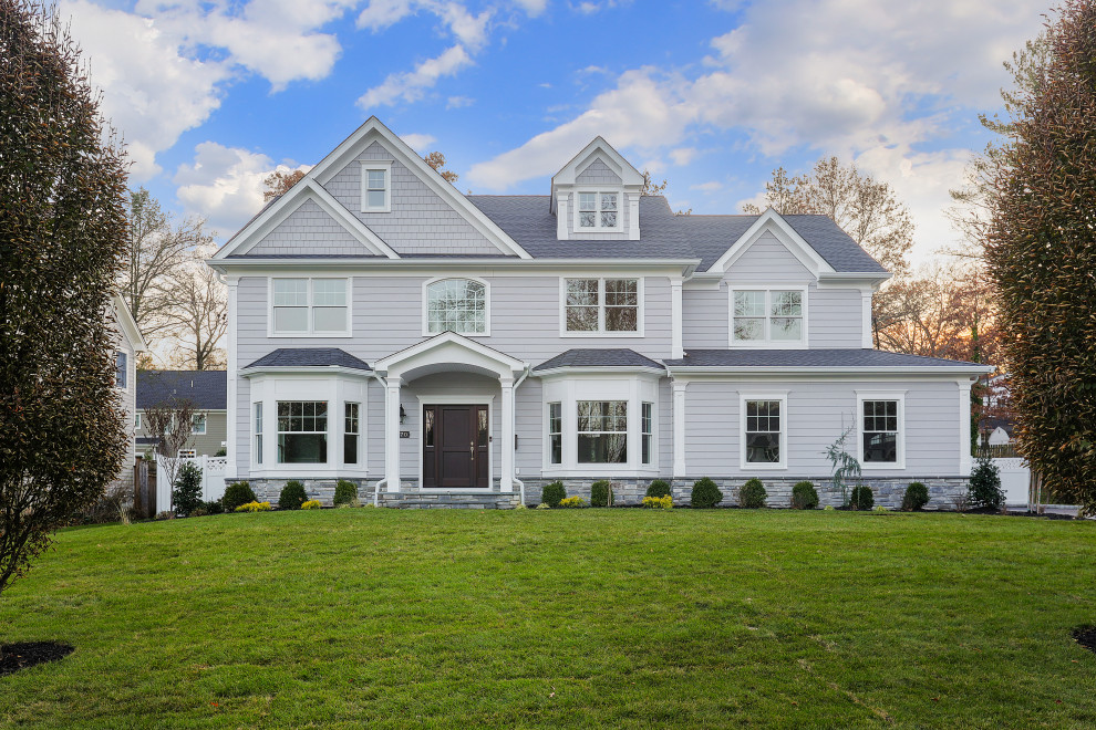 Traditional three-storey grey house exterior in New York with a shingle roof, a grey roof and clapboard siding.
