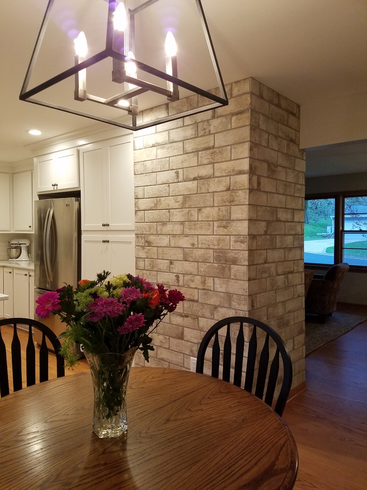 Inspiration for a mid-sized transitional u-shaped medium tone wood floor and brown floor eat-in kitchen remodel with an undermount sink, shaker cabinets, white cabinets, quartz countertops, white backsplash, subway tile backsplash, stainless steel appliances and a peninsula