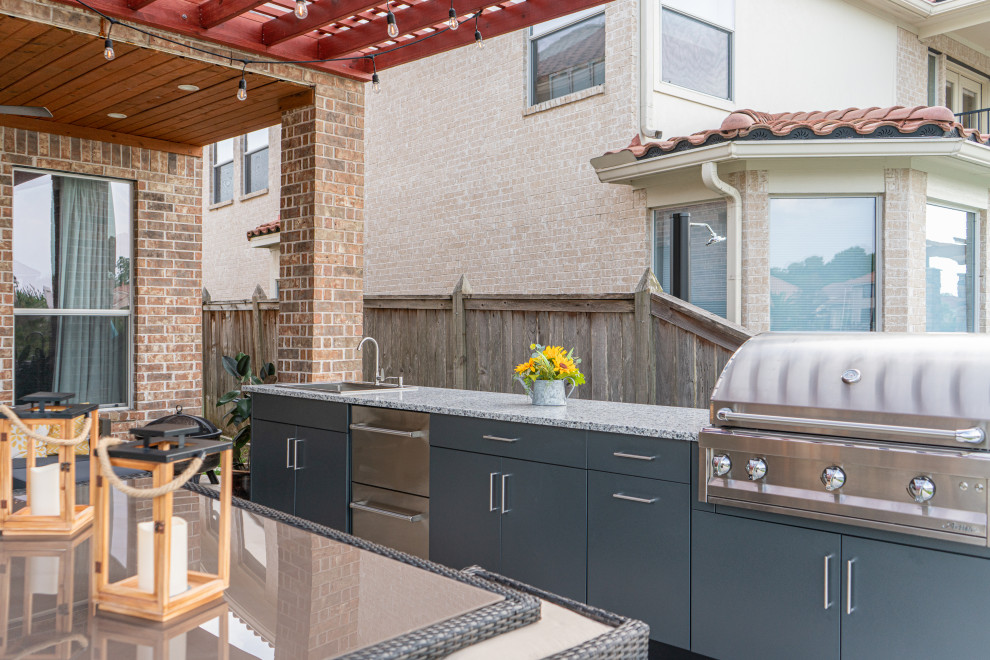 Inspiration for a small contemporary backyard patio in Houston with an outdoor kitchen, natural stone pavers and a pergola.