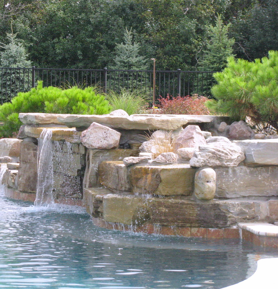 Photo of a large modern backyard custom-shaped natural pool in Detroit with concrete pavers and a water feature.