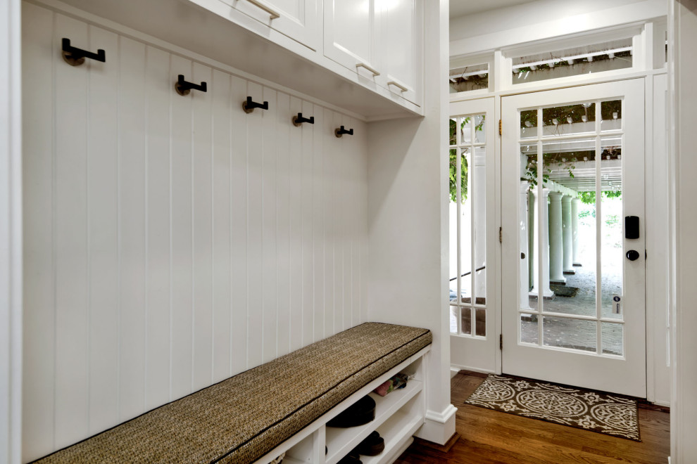 Aménagement d'une entrée classique de taille moyenne avec un vestiaire, un mur blanc, un sol en bois brun, une porte double, une porte blanche, un sol marron et du lambris.