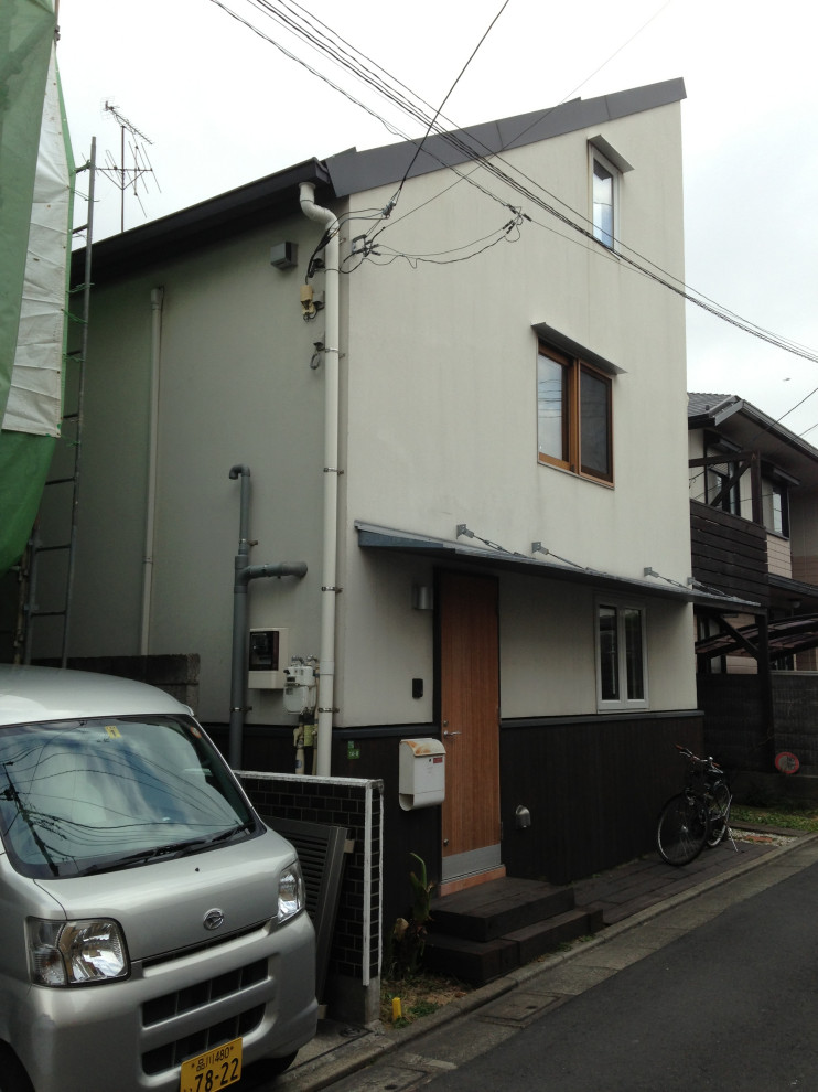 Design ideas for a mid-sized modern three-storey beige house exterior in Tokyo with a shed roof and a metal roof.
