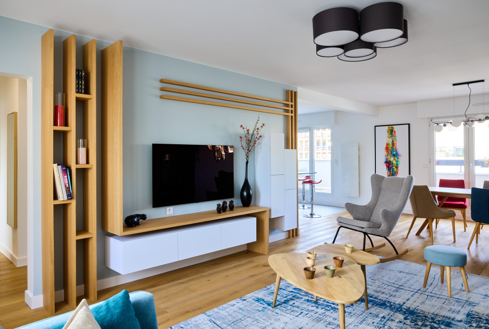 Cette image montre un salon design avec un mur bleu, un sol en bois brun, un téléviseur fixé au mur et un sol marron.
