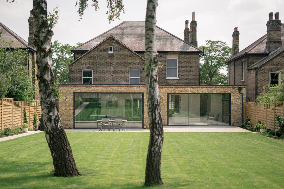 This is an example of a mid-sized contemporary one-storey brick brown house exterior in London with a grey roof.