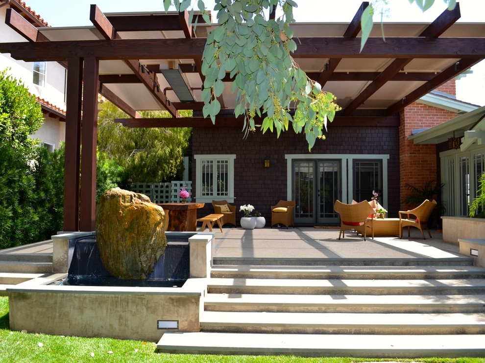 Mid-sized asian backyard patio in Los Angeles with a water feature and a roof extension.