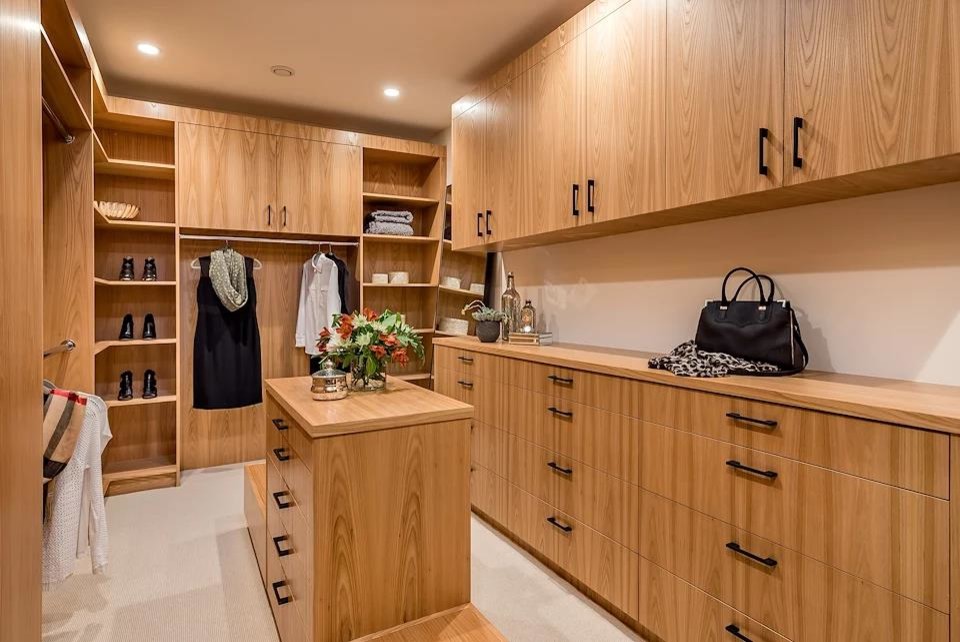 This is an example of a mid-sized modern gender-neutral walk-in wardrobe in San Francisco with flat-panel cabinets, medium wood cabinets, carpet and white floor.