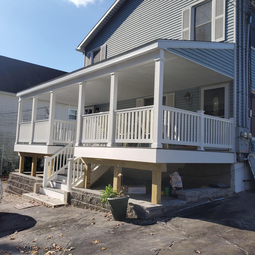 Photo of a large traditional front yard verandah in Bridgeport with with columns, concrete slab, an awning and mixed railing.