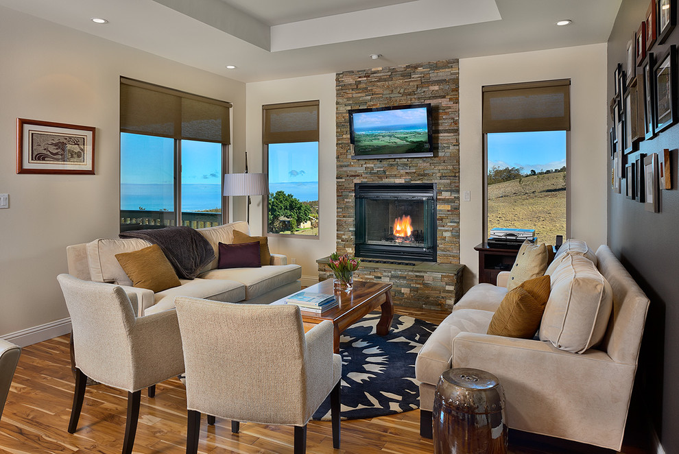 Inspiration for a small traditional formal open concept living room in Hawaii with beige walls, light hardwood floors, a wall-mounted tv, a standard fireplace and a stone fireplace surround.