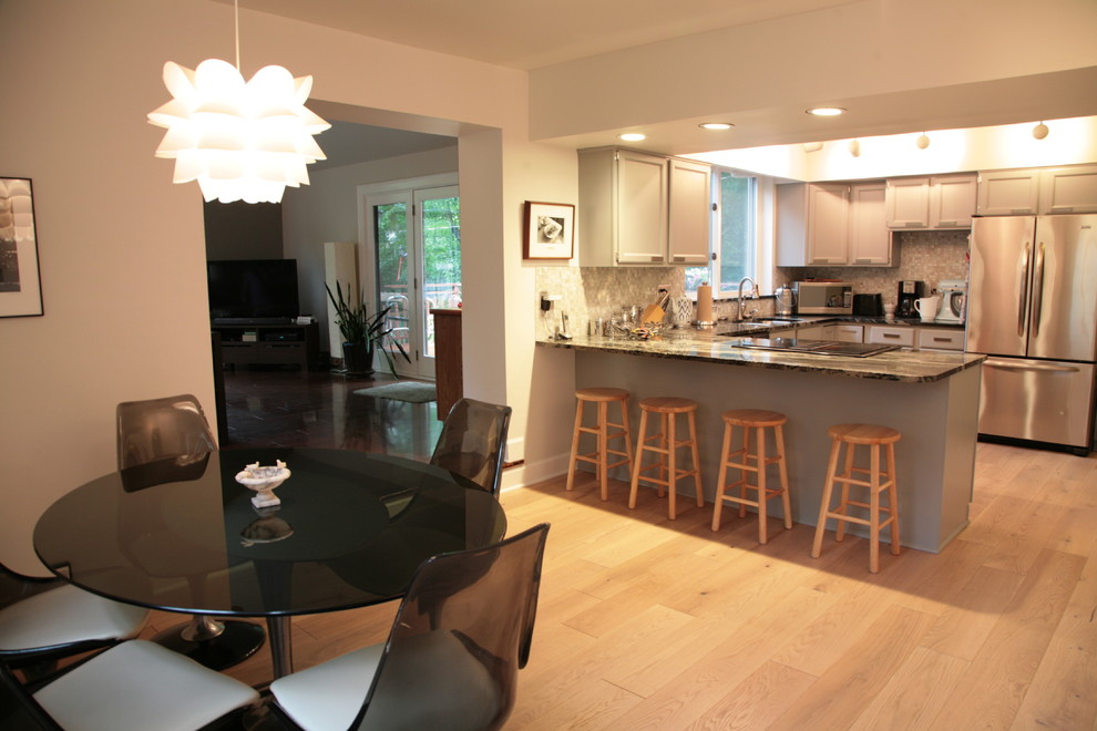 Inspiration for a small transitional u-shaped light wood floor kitchen remodel in Indianapolis with a double-bowl sink, recessed-panel cabinets, beige cabinets, granite countertops, beige backsplash, mosaic tile backsplash, stainless steel appliances and a peninsula
