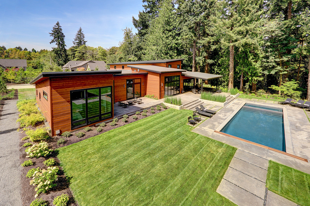 Large contemporary backyard rectangular lap pool in Portland with a pool house and concrete pavers.