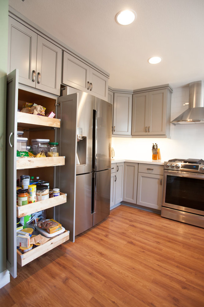 Inspiration for a large transitional u-shaped dark wood floor eat-in kitchen remodel in Los Angeles with an undermount sink, recessed-panel cabinets, gray cabinets, quartz countertops, white backsplash, subway tile backsplash, stainless steel appliances and no island