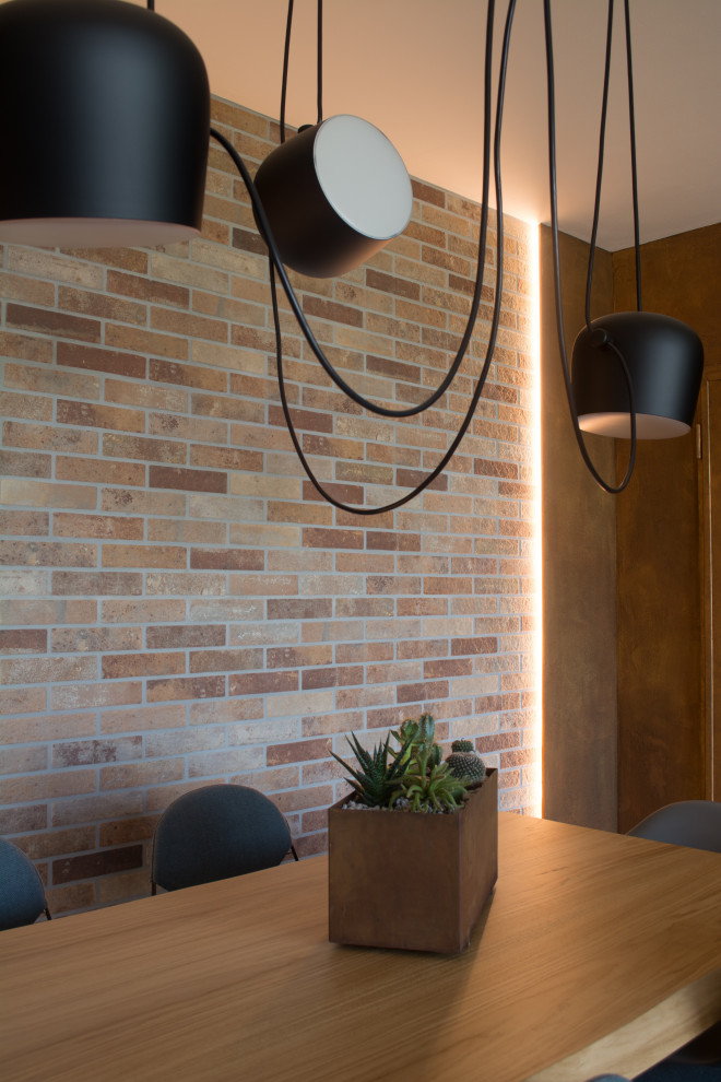 Aménagement d'une salle à manger ouverte sur le salon industrielle de taille moyenne avec parquet clair et un mur en parement de brique.