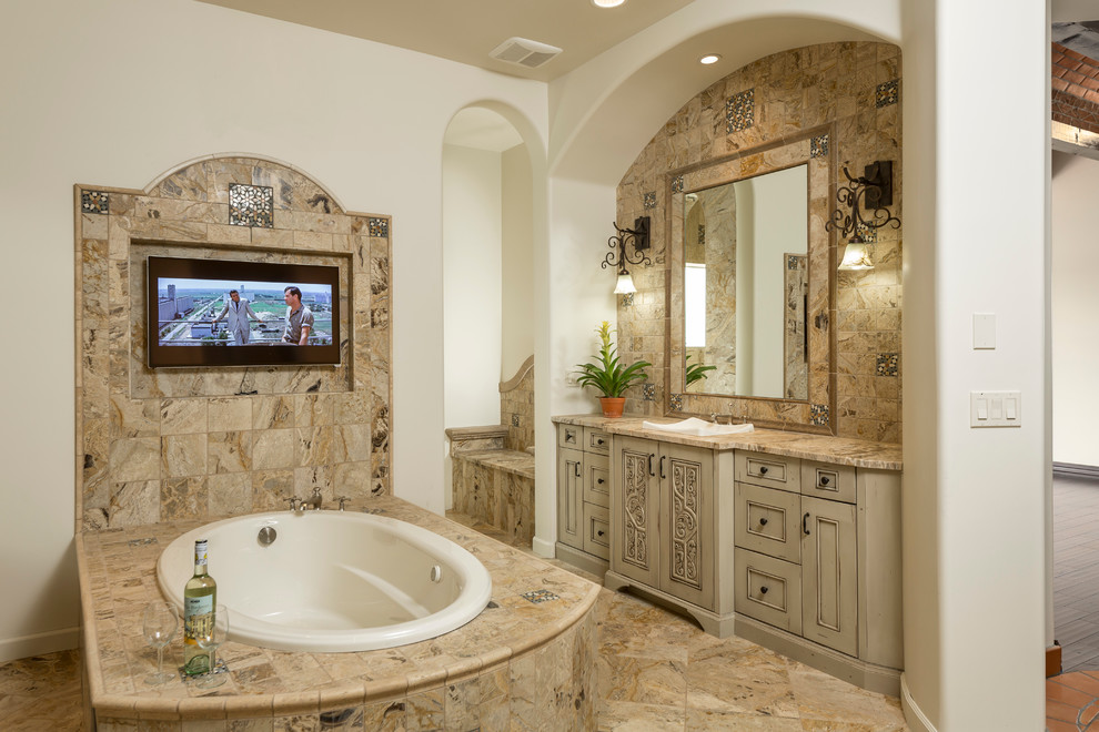 Design ideas for a mid-sized mediterranean master bathroom in Phoenix with a drop-in sink, recessed-panel cabinets, beige cabinets, granite benchtops, a drop-in tub, multi-coloured tile, stone tile, white walls and travertine floors.
