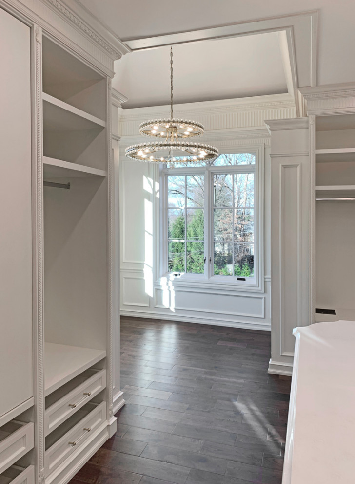 Inspiration for a large timeless gender-neutral dark wood floor and brown floor built-in closet remodel in New York with shaker cabinets and white cabinets