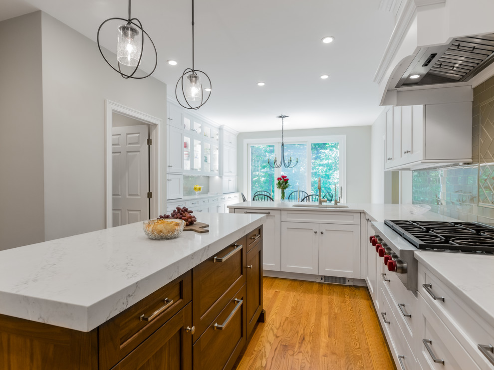Example of a large transitional u-shaped light wood floor and brown floor eat-in kitchen design in Boston with an undermount sink, recessed-panel cabinets, white cabinets, quartz countertops, gray backsplash, glass tile backsplash, stainless steel appliances, an island and white countertops