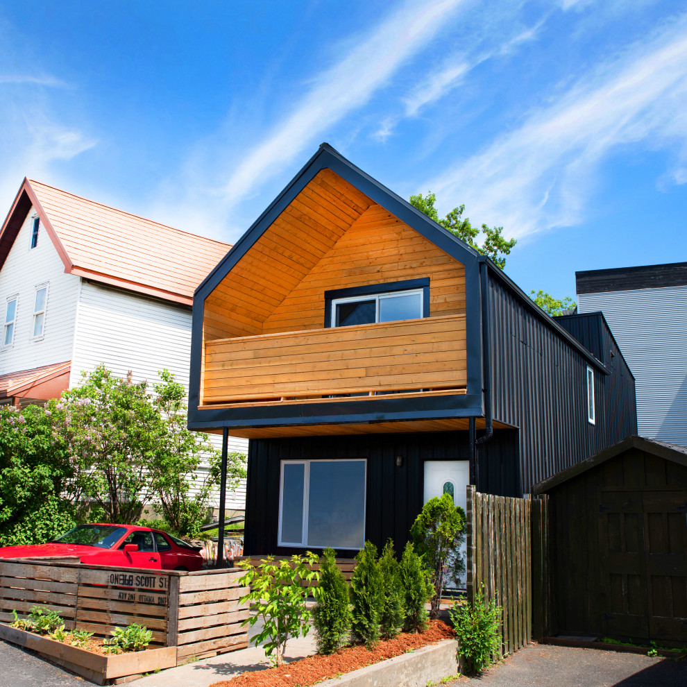 Idée de décoration pour une petite façade de maison métallique et noire minimaliste en planches et couvre-joints à un étage avec un toit à quatre pans, un toit en métal et un toit noir.