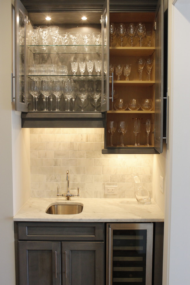 This is an example of a small modern single-wall wet bar in Miami with an undermount sink, shaker cabinets, grey cabinets, marble benchtops, grey splashback, marble splashback, dark hardwood floors and brown floor.