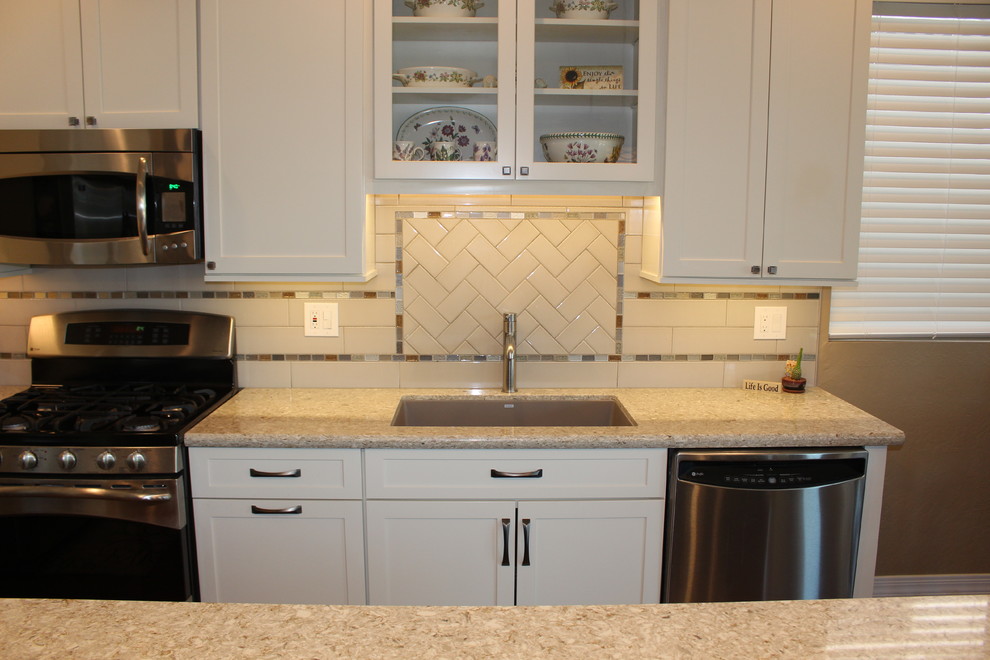 Inspiration for a mid-sized transitional l-shaped dark wood floor and brown floor open concept kitchen remodel in Phoenix with an undermount sink, shaker cabinets, white cabinets, granite countertops, white backsplash, subway tile backsplash, stainless steel appliances and an island