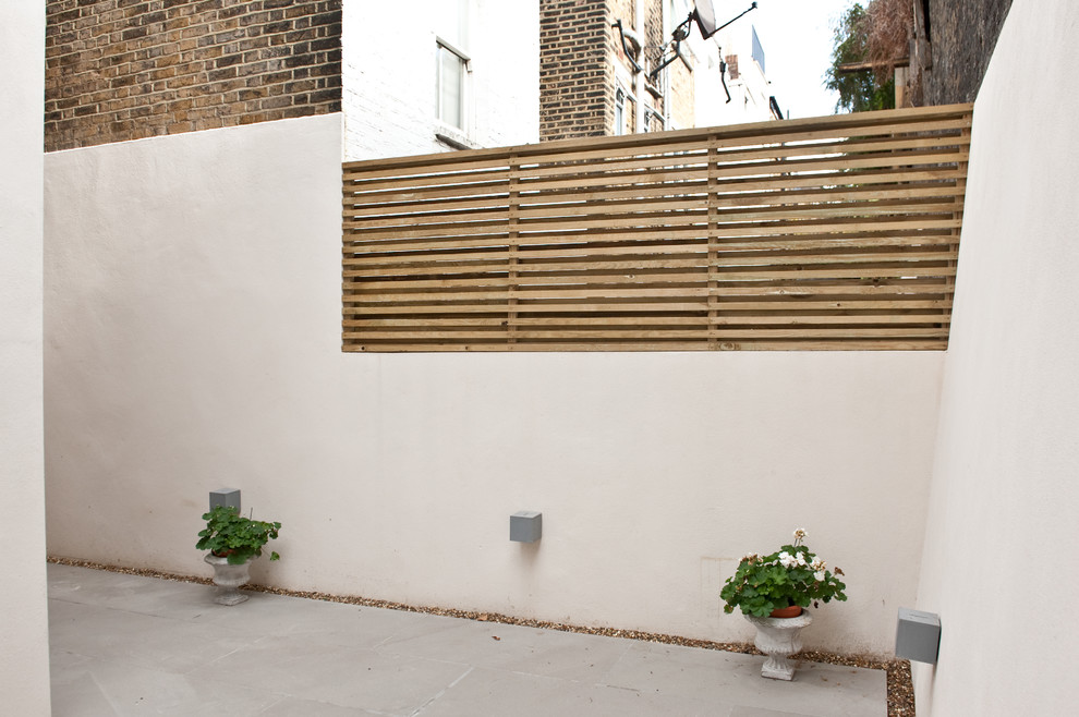 This is an example of a mid-sized contemporary backyard patio in London with concrete pavers and no cover.