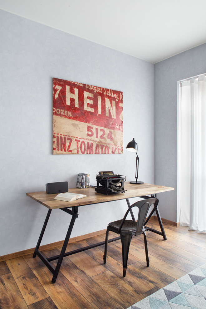 Photo of a mid-sized industrial home office in Milan with medium hardwood floors, a freestanding desk and blue walls.