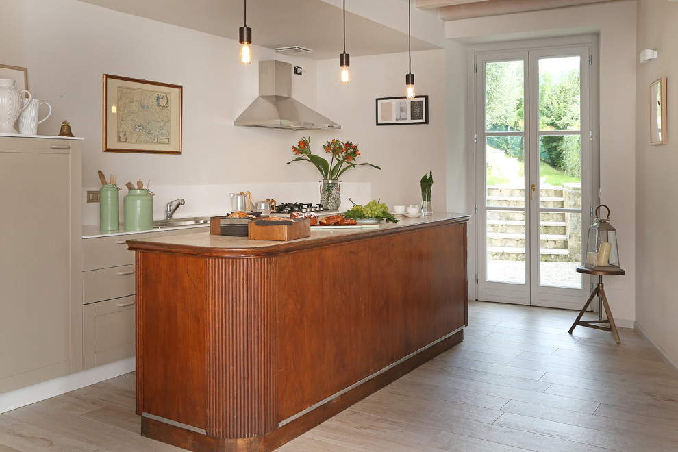 Photo of a mid-sized country single-wall open plan kitchen in Milan with a drop-in sink, flat-panel cabinets, beige cabinets, laminate floors, with island and beige floor.