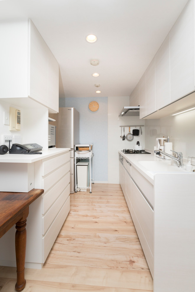 東京23区にある北欧スタイルのおしゃれなII型キッチン (一体型シンク、フラットパネル扉のキャビネット、白いキャビネット、白いキッチンパネル、淡色無垢フローリング、茶色い床) の写真