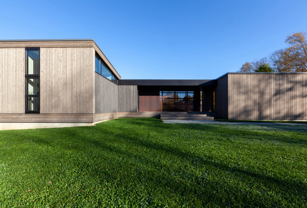 Cette image montre une façade de maison grise minimaliste en bois et bardage à clin de plain-pied et de taille moyenne avec un toit en appentis, un toit en métal et un toit gris.