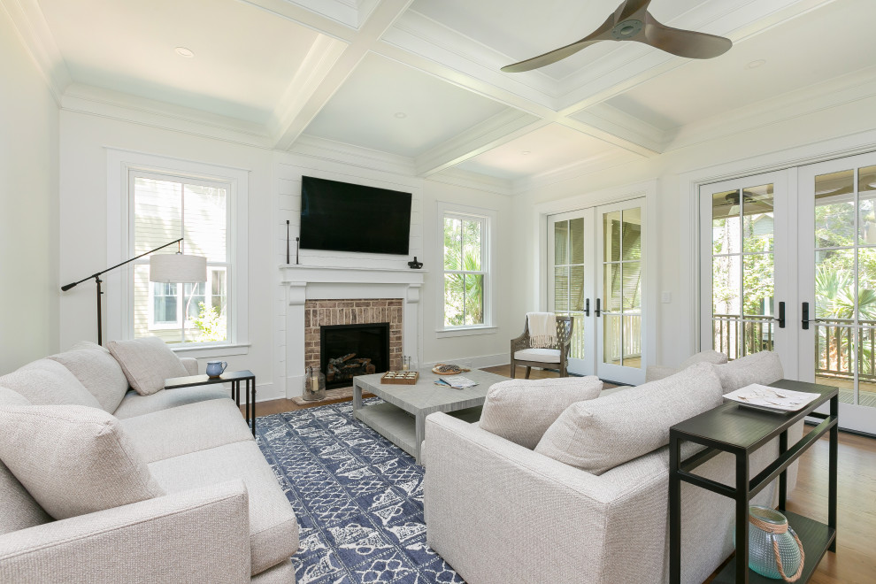 This is an example of a large transitional open concept living room in Charleston with white walls, dark hardwood floors, a standard fireplace, a wall-mounted tv, brown floor and coffered.