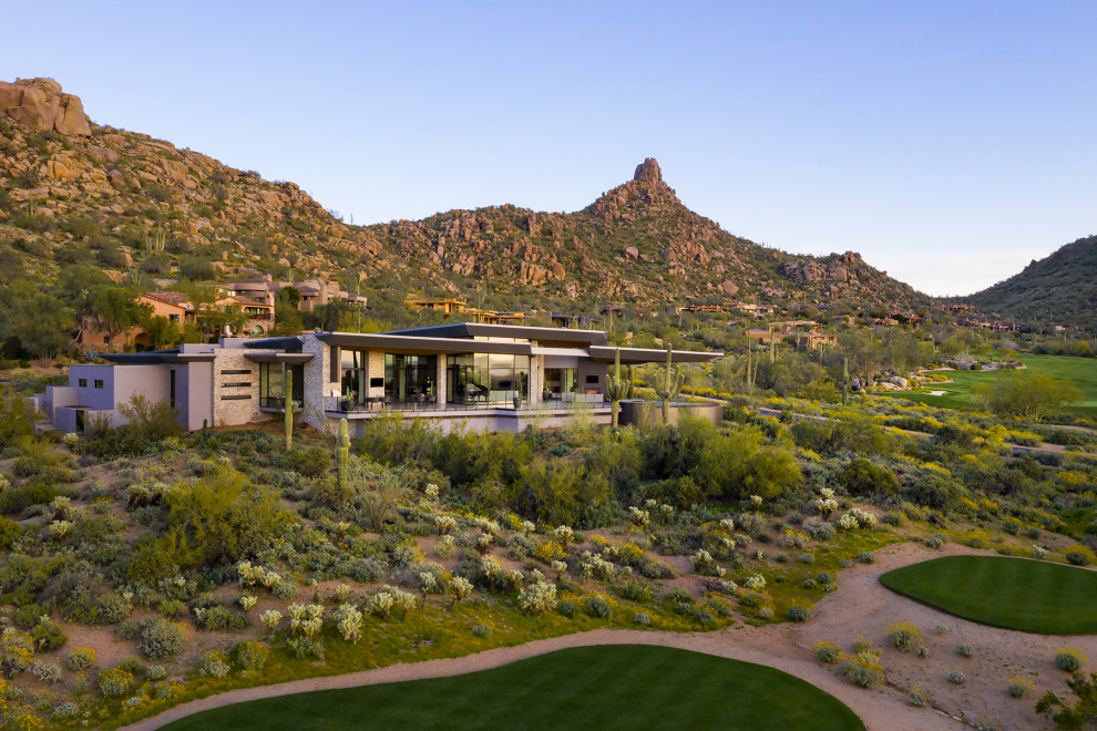 Inspiration for an expansive modern house exterior in Phoenix with stone veneer, a butterfly roof and a metal roof.