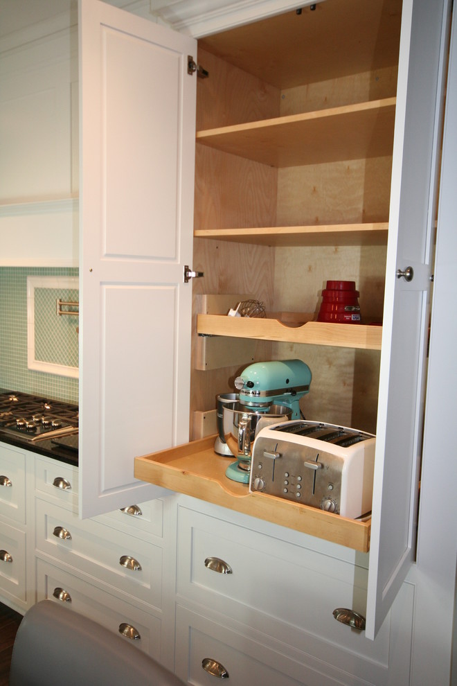 Enclosed kitchen - mid-sized transitional u-shaped porcelain tile and brown floor enclosed kitchen idea with a farmhouse sink, shaker cabinets, white cabinets, quartzite countertops, green backsplash, glass tile backsplash, white appliances, an island and black countertops
