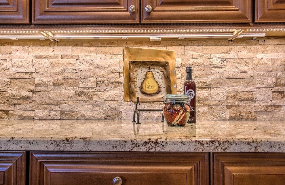 Open concept kitchen - large transitional l-shaped brown floor open concept kitchen idea in Phoenix with a double-bowl sink, raised-panel cabinets, dark wood cabinets, granite countertops, beige backsplash, stone tile backsplash, stainless steel appliances and an island